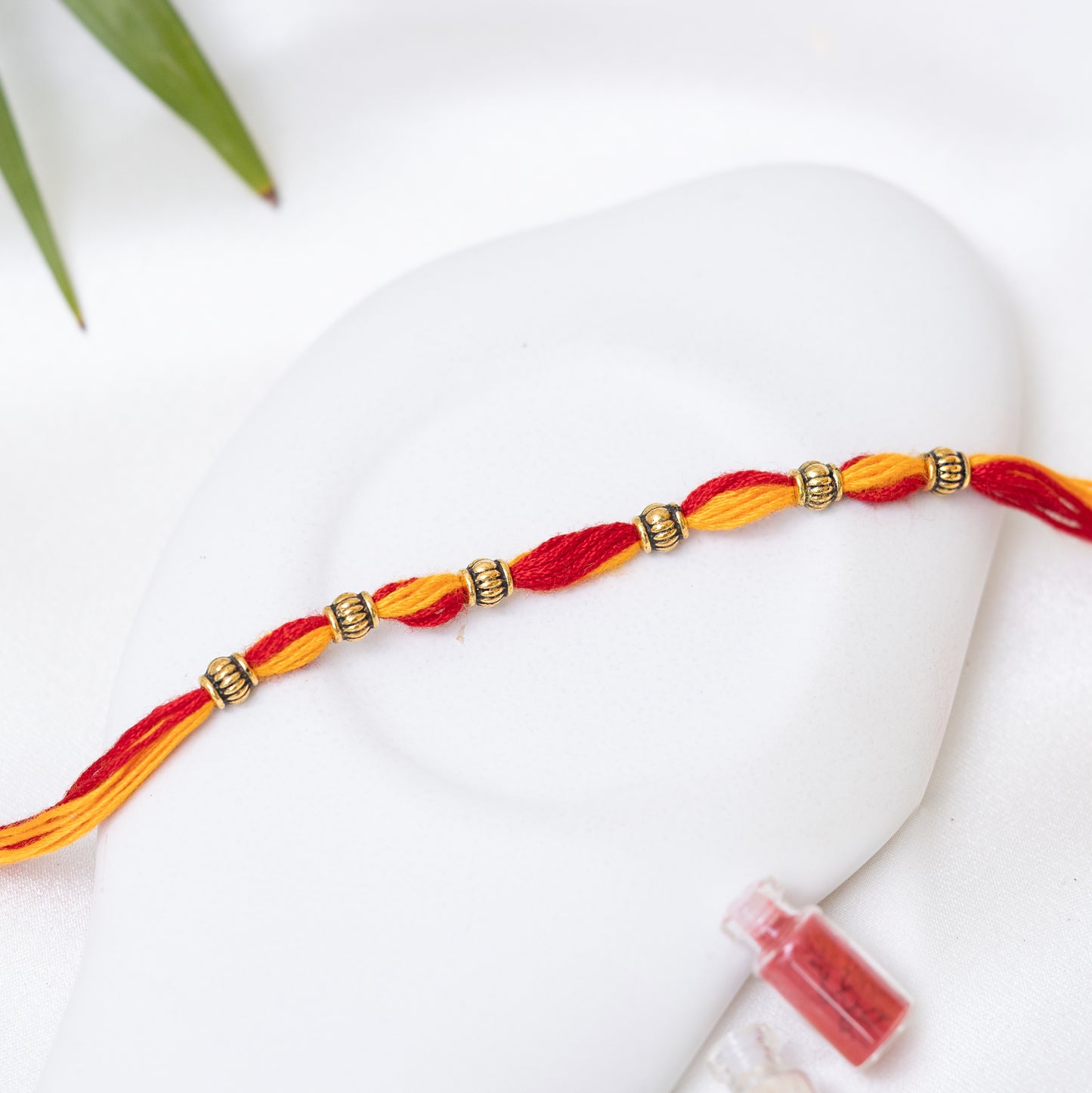 Red-Yellow Rakhi with small Antique Charm set of 3 with Roli Chawal Set