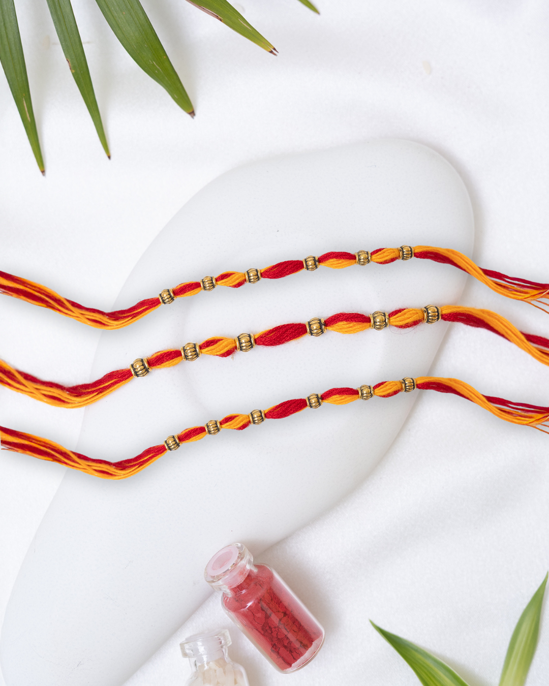 Red-Yellow Rakhi with small Antique Charm set of 3 with Roli Chawal Set