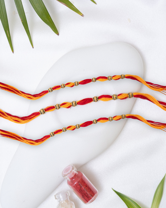 Red-Yellow Rakhi with small Antique Charm set of 3 with Roli Chawal Set